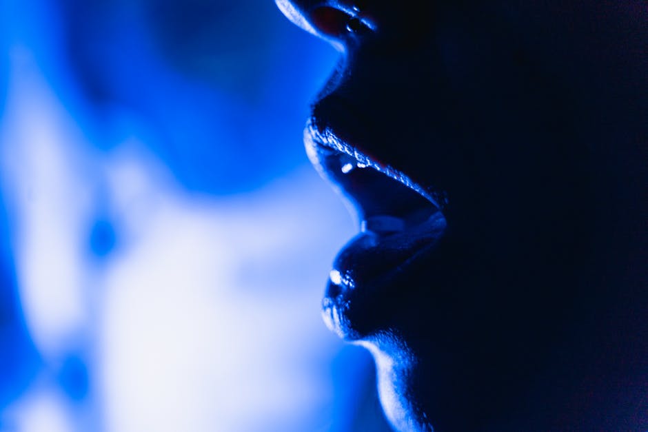 Close-up abstract image of an open mouth silhouette in dramatic blue lighting.