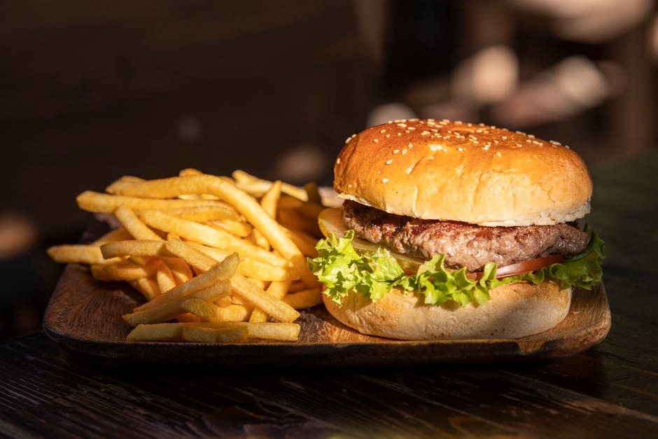 Close-up of a tasty cheeseburger and crispy french fries on a wooden platter.