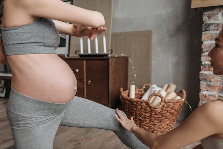 Pregnant woman doing yoga indoors with instructor assistance, emphasizing fitness and well-being.