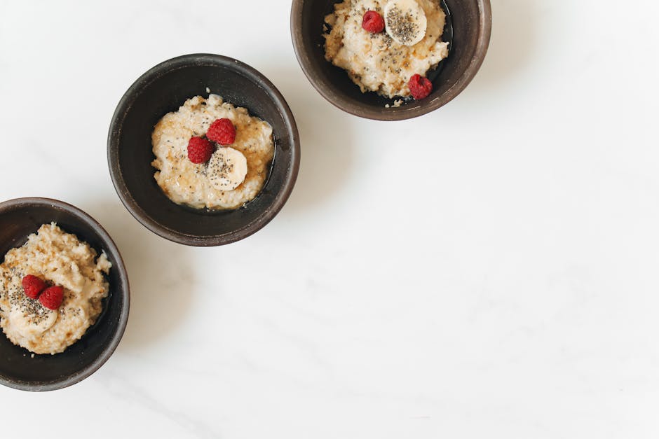 Bowl of oatmeal with banana, raspberry, and chia seeds on a white background.