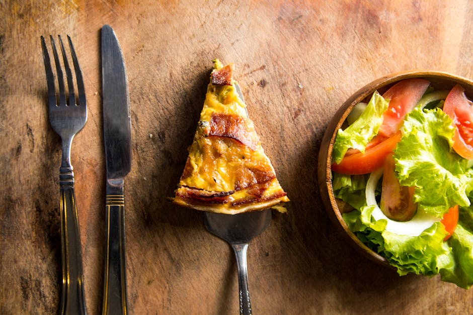 A delicious slice of quiche served with fresh vegetable salad on a rustic wooden table.